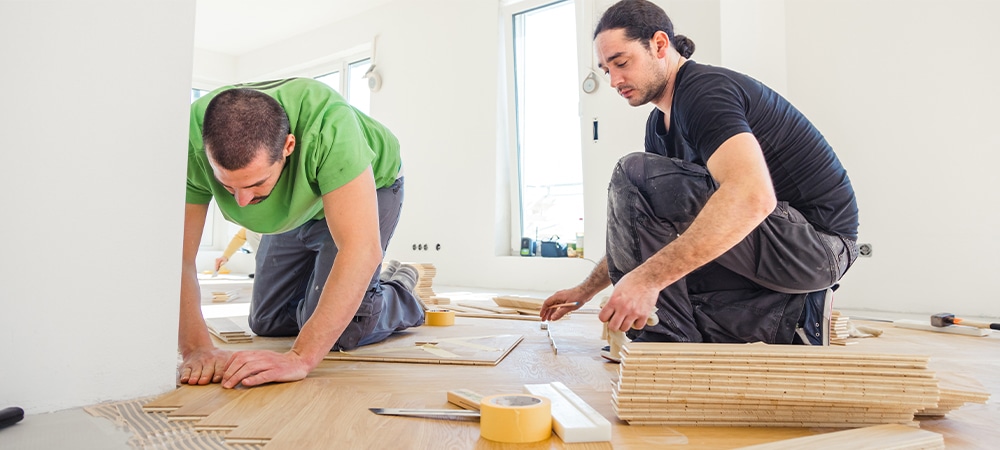 carpenters on work putting wood parquet pieces, installing chevron wood floor