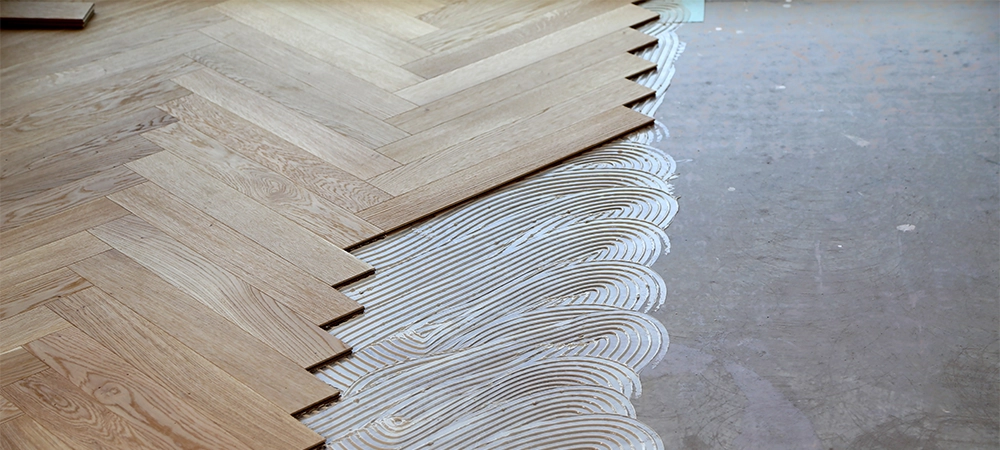 A worker laying parquet flooring and installing wooden laminate