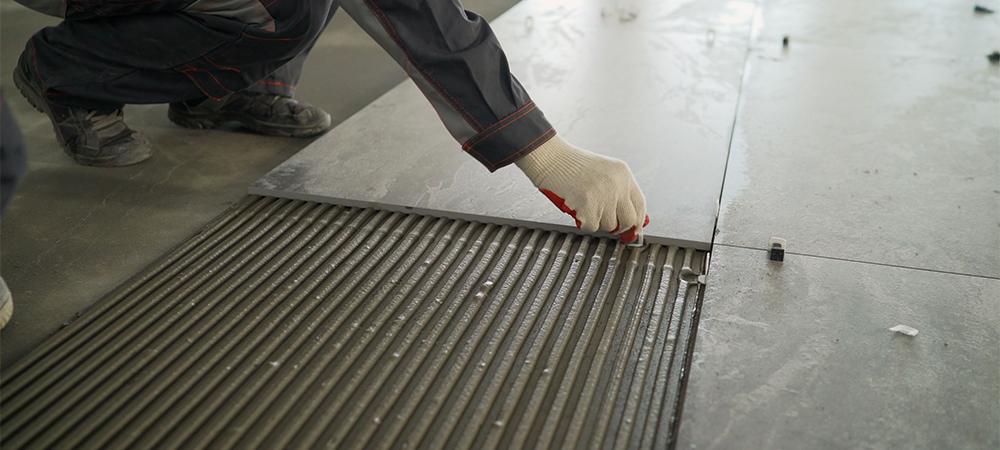 installing a large ceramic tile, workers lay large tiles on the floor