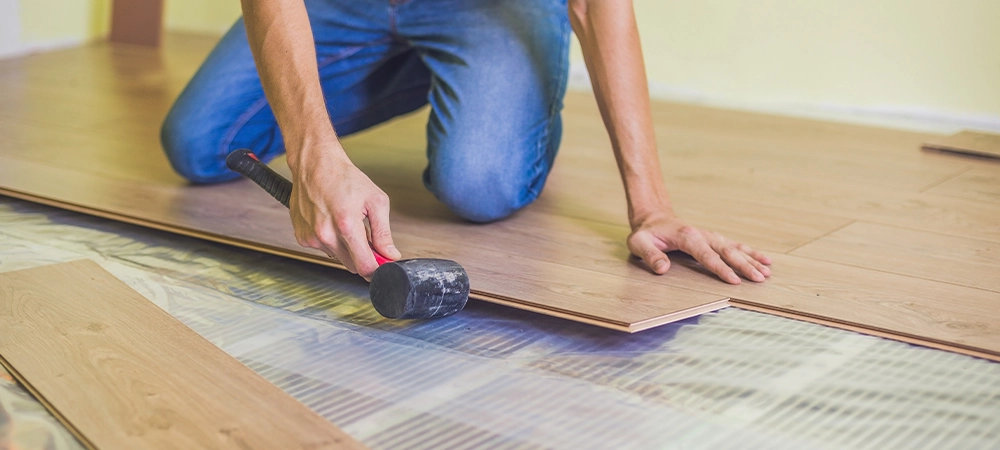 Man installing new wooden laminate flooring on a warm film floor. infrared floor heating system under laminate floor