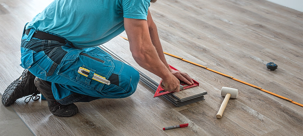 Floating floor work. The worker shortening the board of vinyl plank by cutting and breaking.