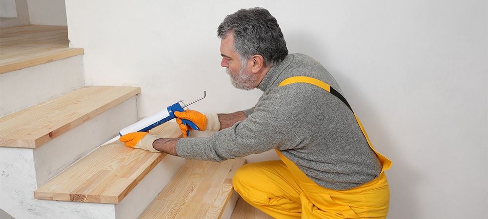 professional man applying sealing protects on wooden stairs