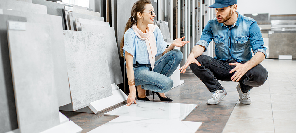 young woman customer choosing tiles standing with seller or repairman in the ceramic shop